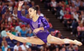 A young girl gymnast performs in a blue gymnastic swimsuit