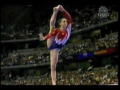 A young girl gymnast performs in a pink gymnastic swimsuit