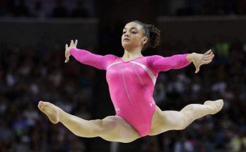 A beautiful young girl gymnast in a pink gymnastic swimsuit