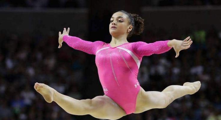 A beautiful young girl gymnast in a pink gymnastic swimsuit