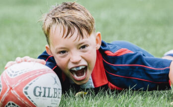 A boy is playing rugby. We can see a mouthguard in his open mouth.